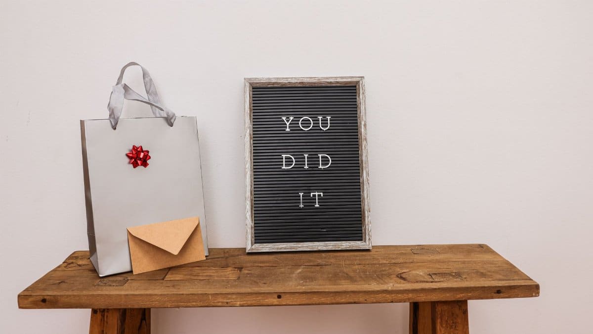 Gift bag with envelope and congratulatory letter board on wooden table.