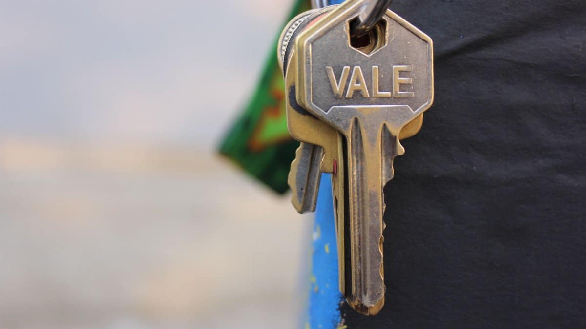 A detailed view of a metallic key with 'Vale' engraved on it, hanging against a blurred background.