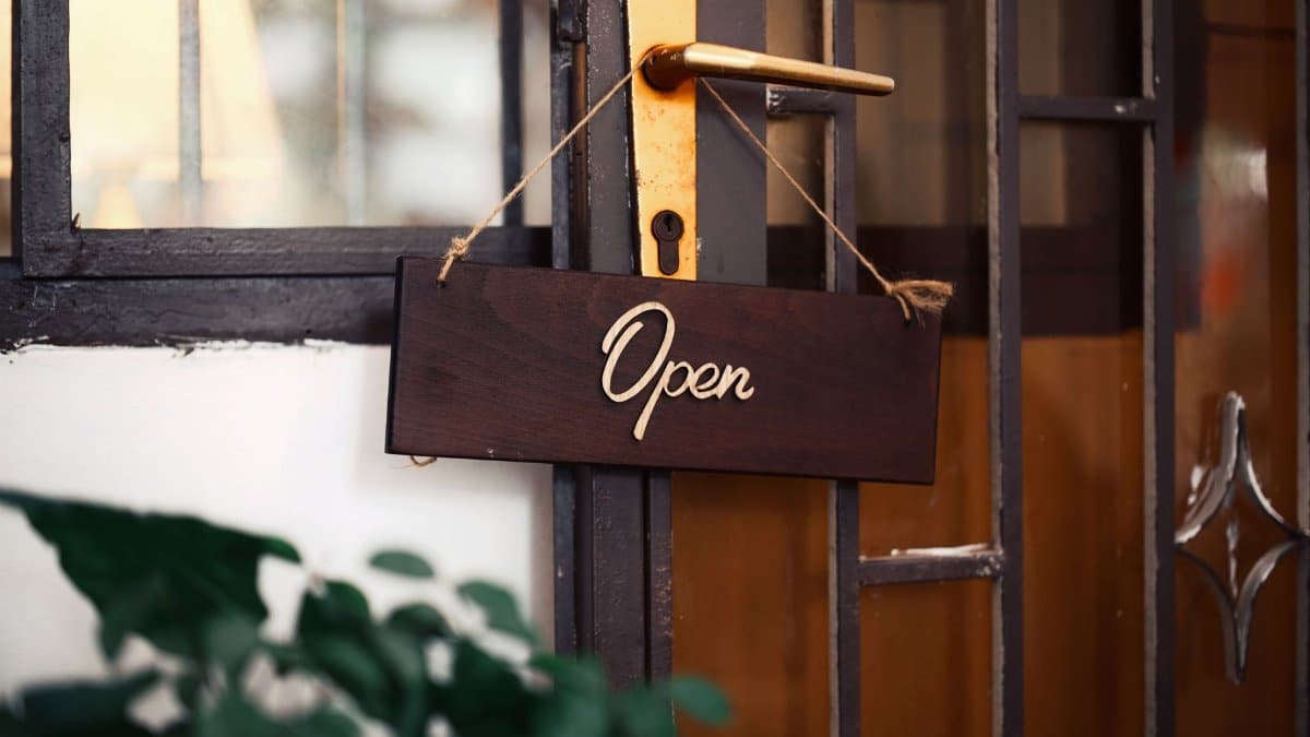 Wooden 'Open' sign hanging on a rustic door, inviting entry.