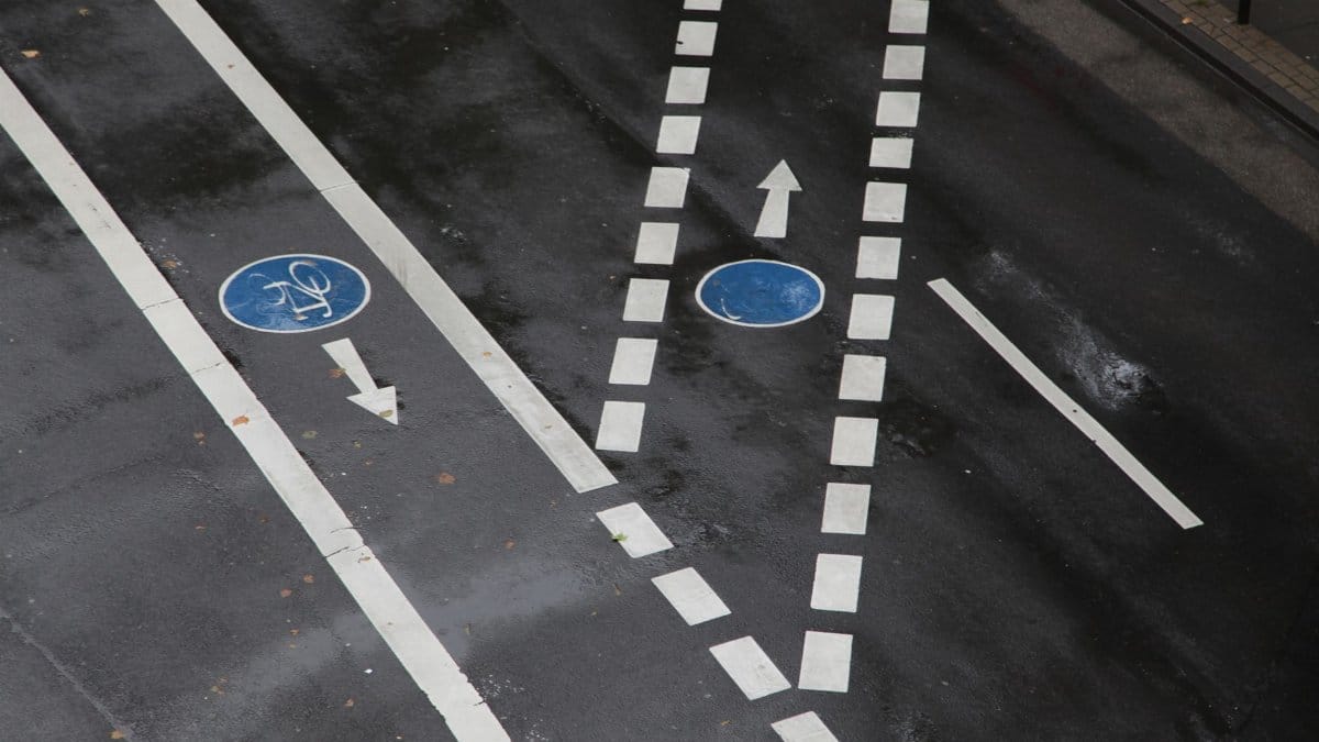 Overhead view of an urban road featuring bicycle lane markings after rain, reflecting a wet surface.