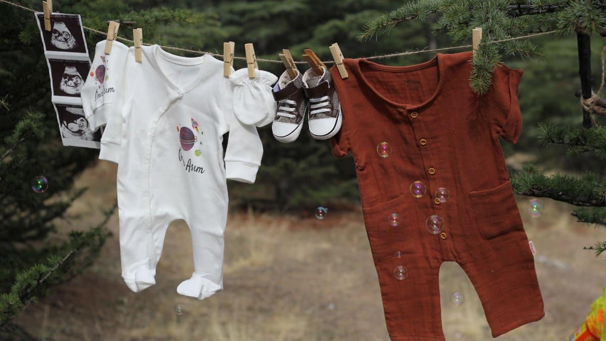 Cute baby clothes hanging outdoors with ultrasound photos, capturing a joyful moment.
