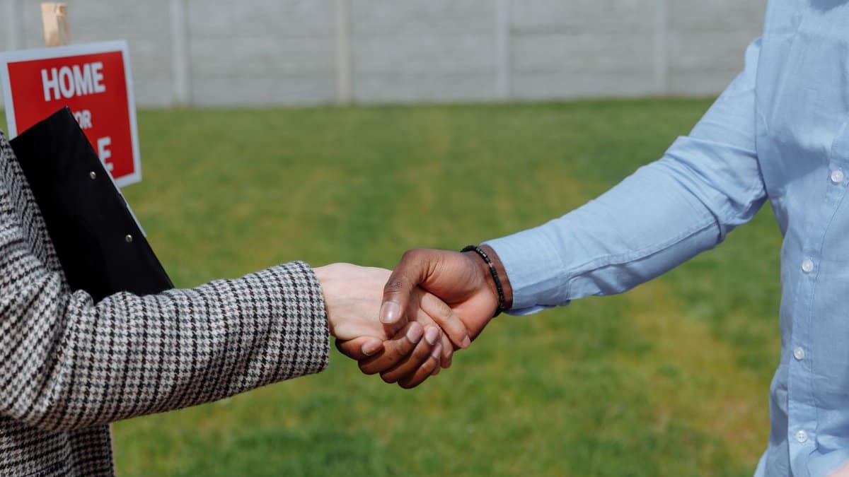 Close-up of a handshake symbolizing a real estate agreement outdoors.