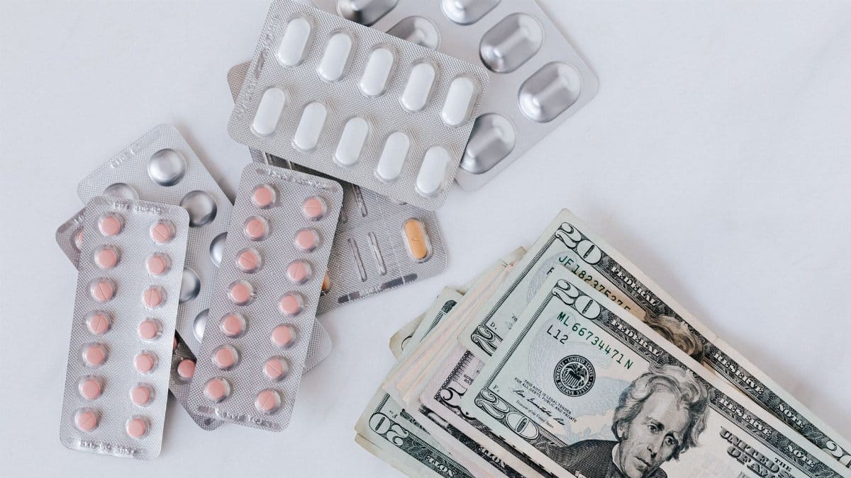 Top view of different blisters of medications and pills composed with heap of paper money