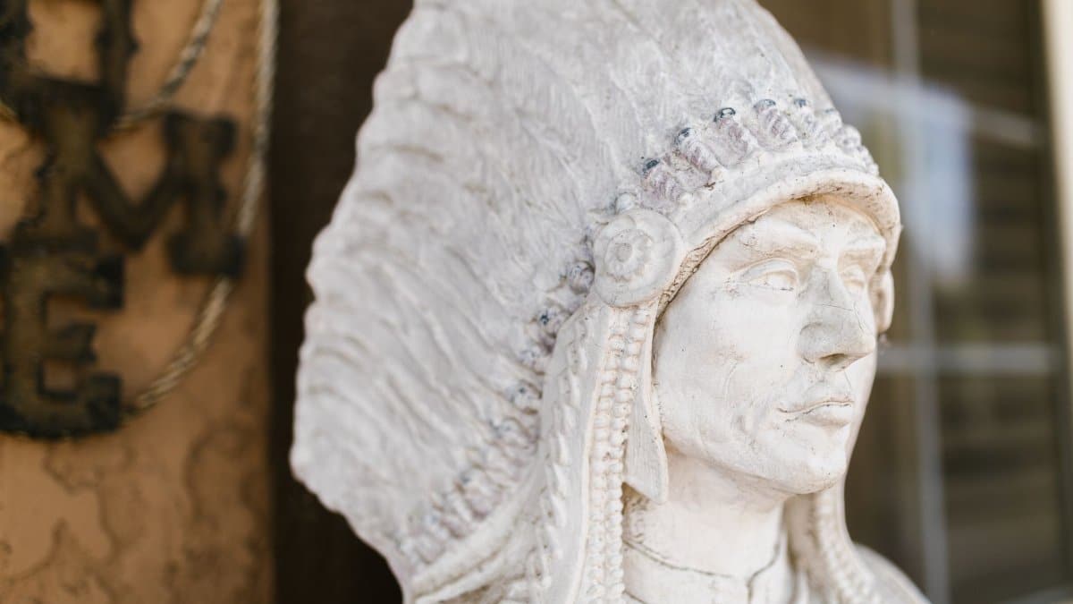 A detailed close-up photo of a stone sculpture depicting a Native American chief with a feathered headdress.