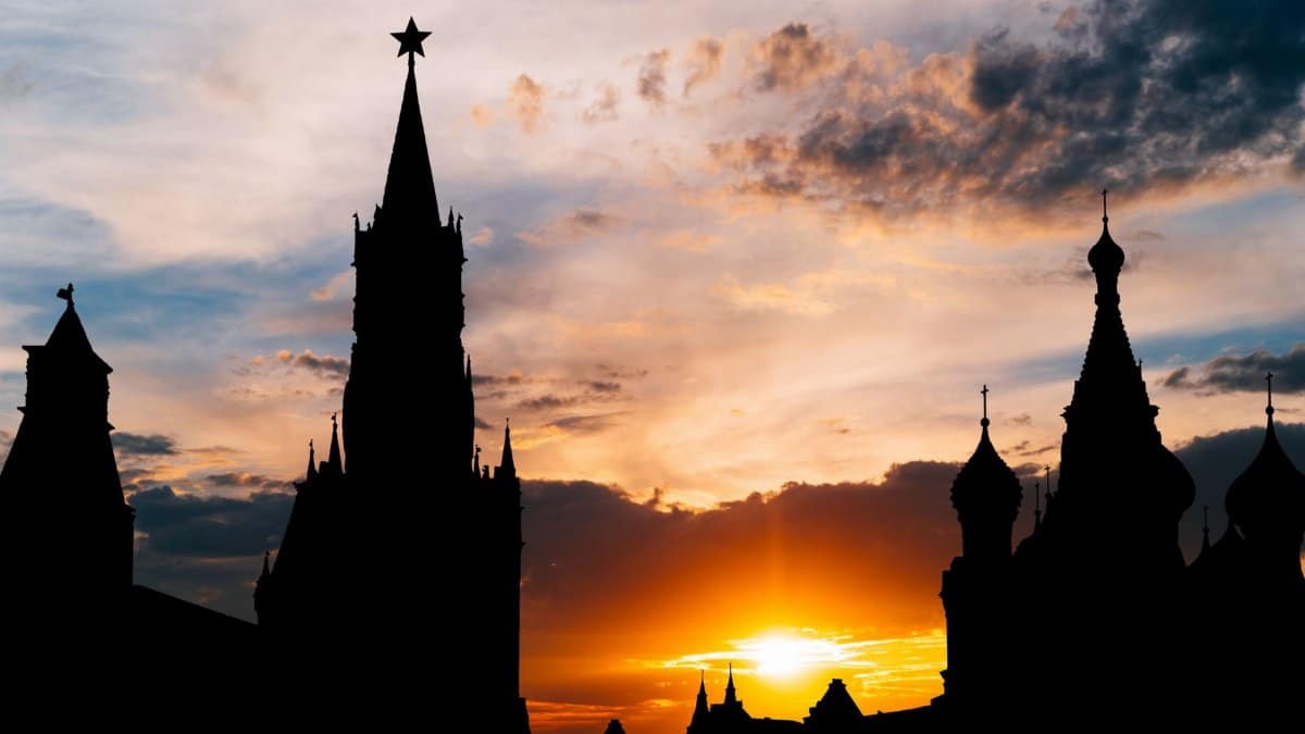 Majestic silhouette of Moscow Kremlin towers at sunset with vibrant orange sky.