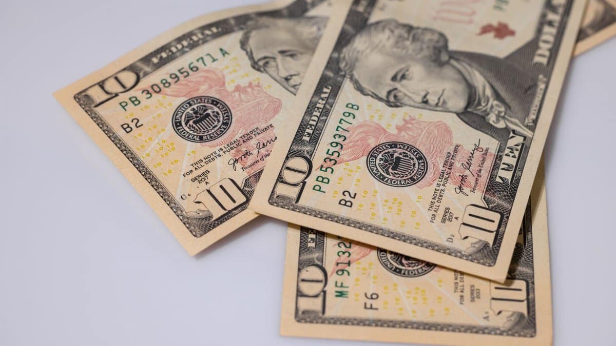 Detailed view of American ten dollar bills scattered on a light surface, showcasing currency features.