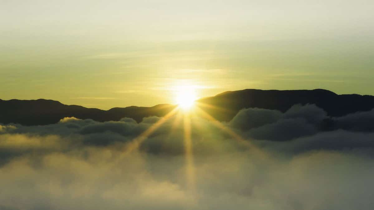 A beautiful sunrise over misty mountains with dazzling sunbeams breaking through the fog.