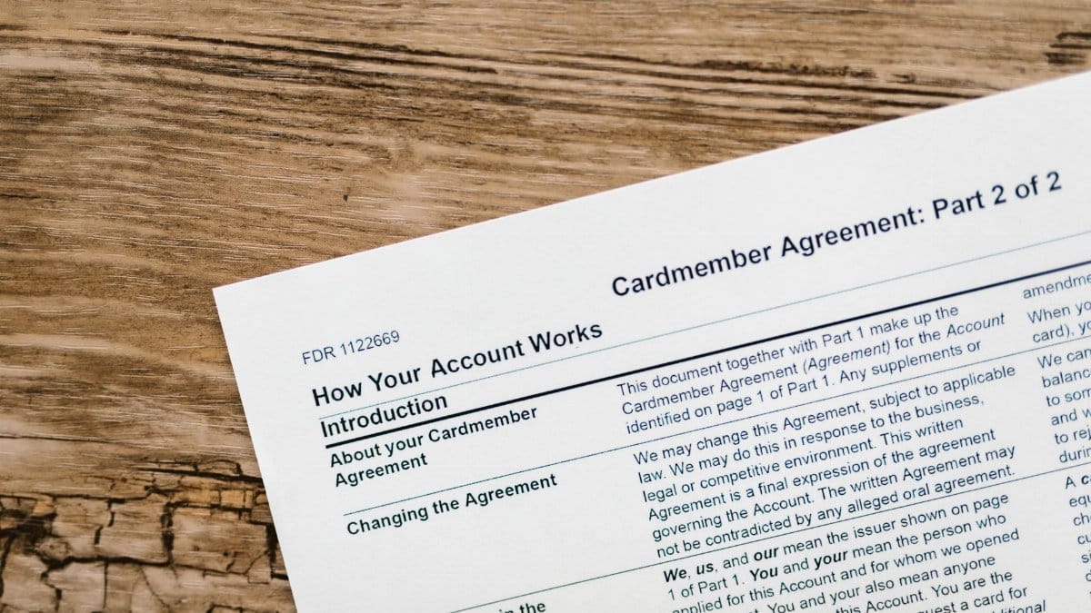 Close-up of a credit card agreement document on a textured wooden desk.