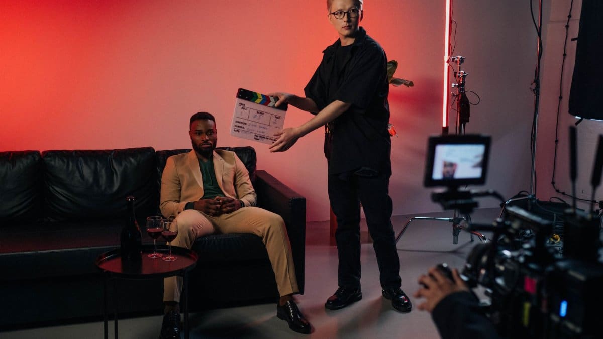 Professional film set with actor in suit, director using clapperboard.