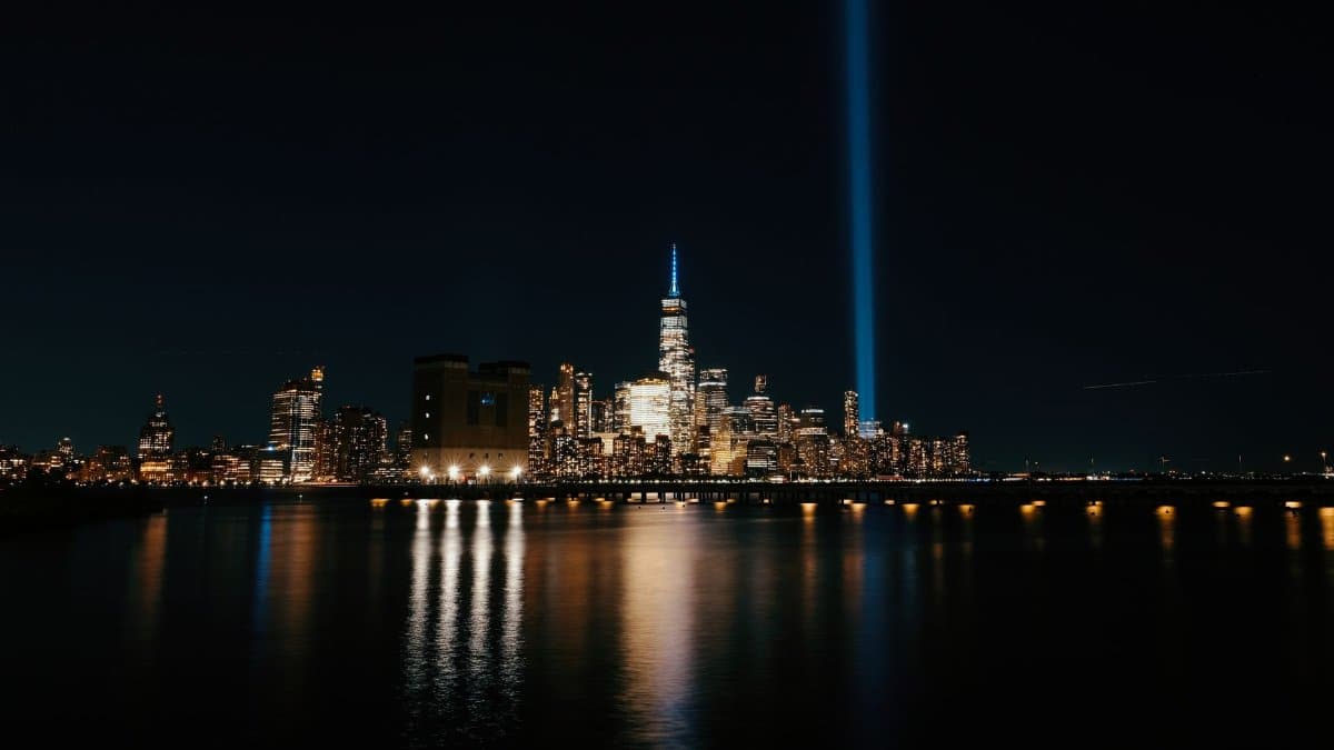 Night view of New York City skyline featuring the Tribute in Light as seen from the water.
