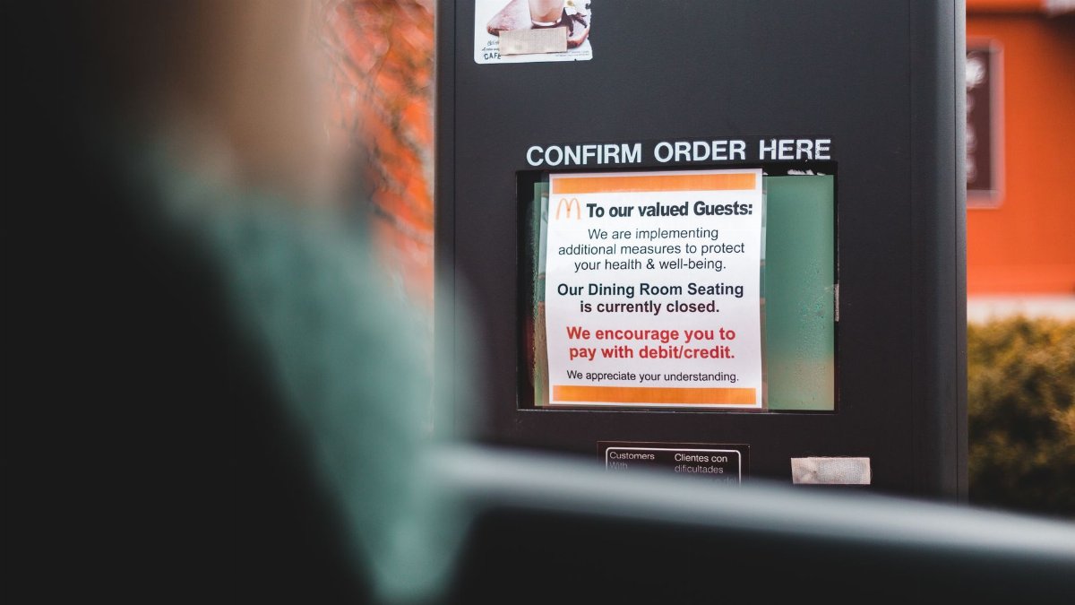 A drive-thru ordering sign with health advisory notice at a fast food restaurant.