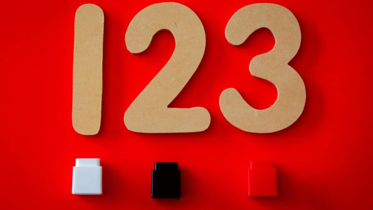 Close-up of wooden numbers 1, 2, 3 with colorful blocks on a vibrant red background.