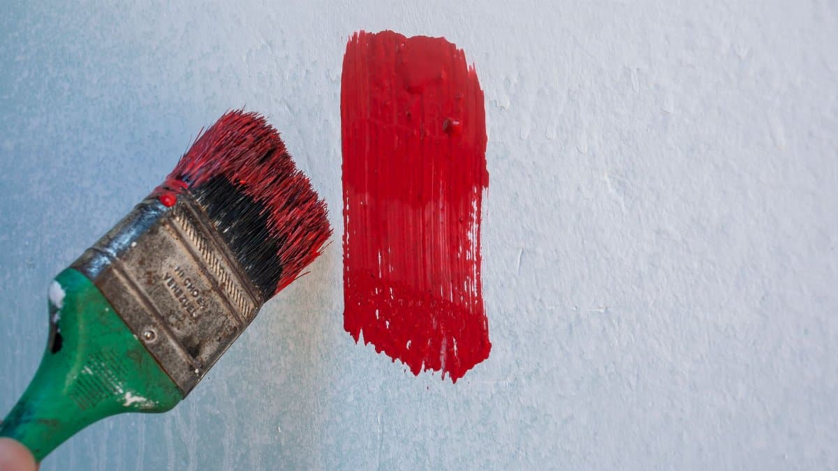 Close-up of a paintbrush applying red paint on a wall in Mérida, Venezuela.