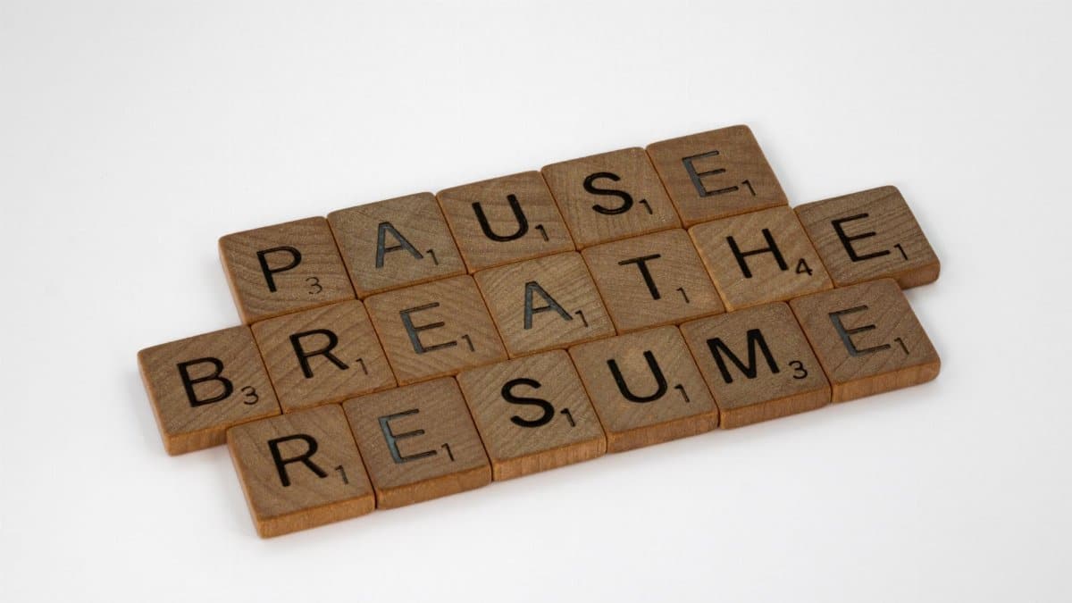 Inspiring words 'Pause Breathe Resume' arranged with scrabble tiles on a white surface.
