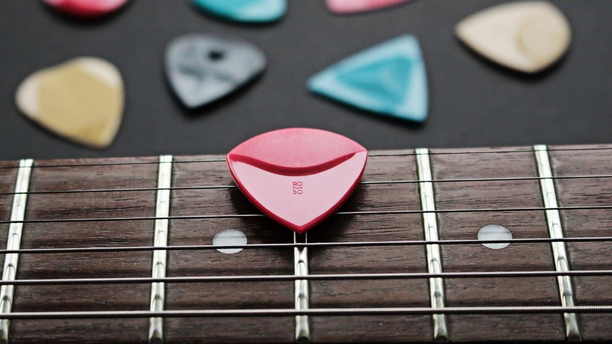 Close-up of a fretboard with colorful guitar picks showcasing musical inspiration.