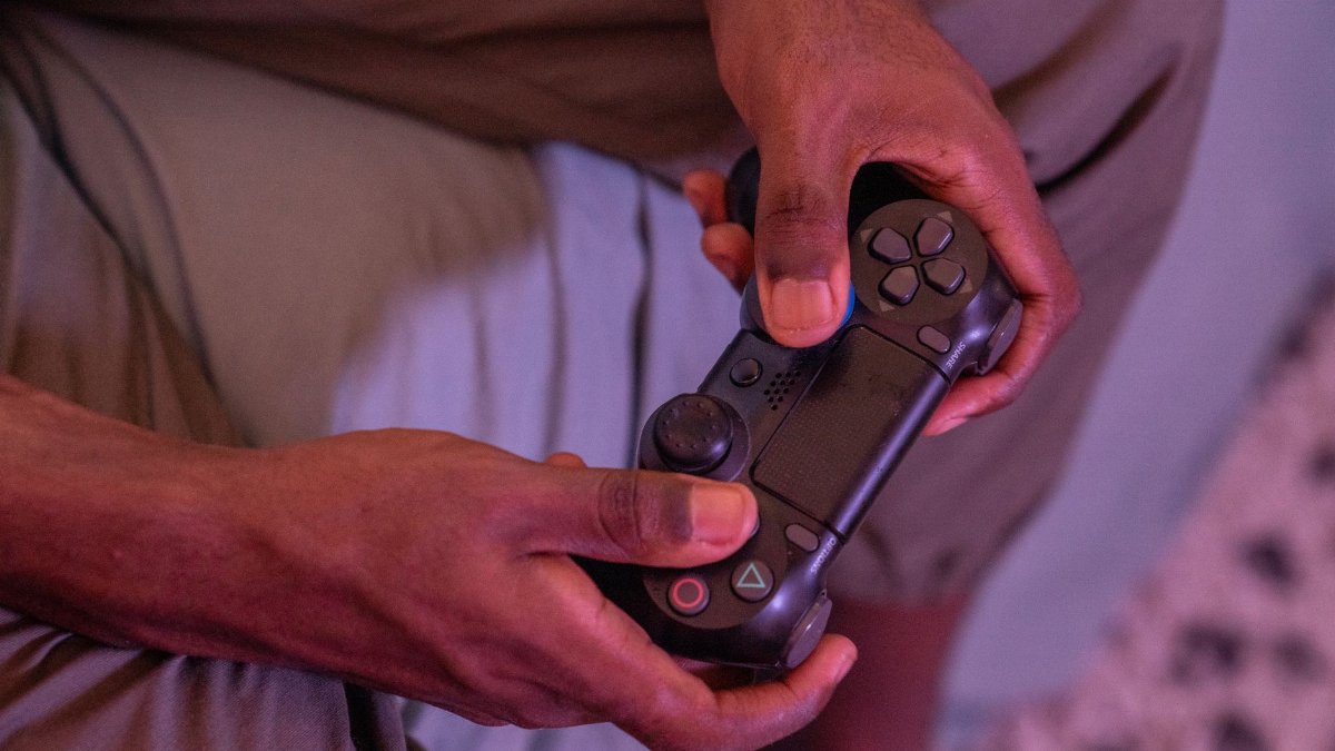 Hands gripping a game controller, engaged in a video game indoors.