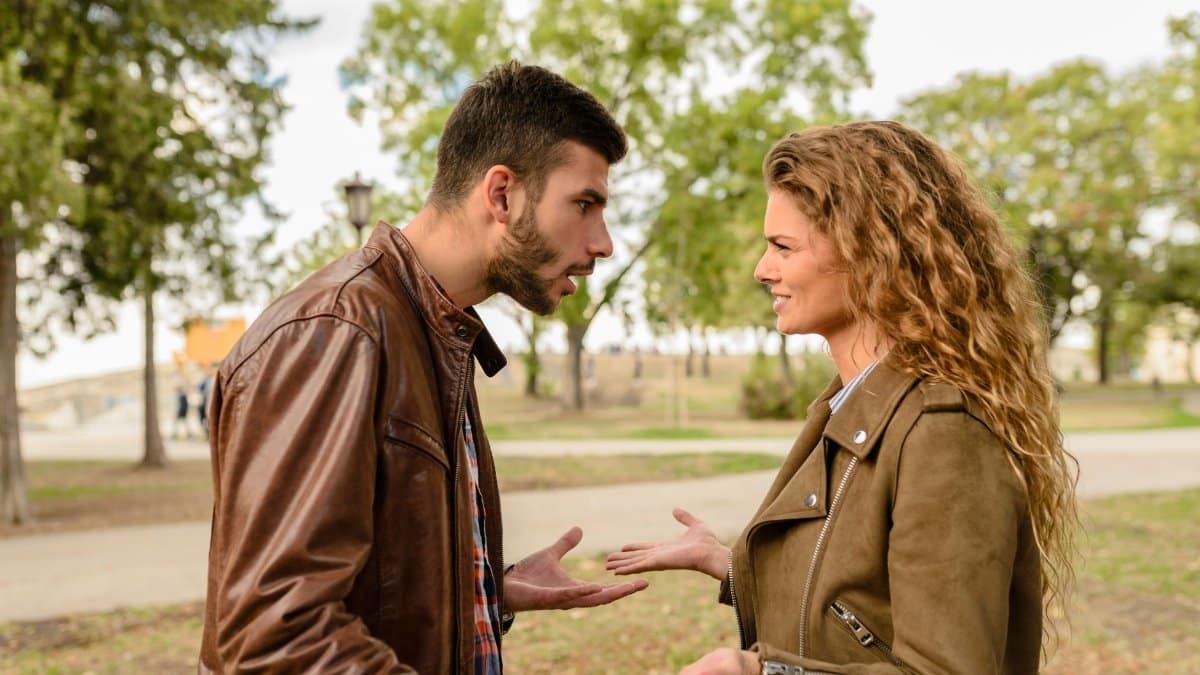 A couple having an argument outdoors, expressing frustration and conflict.