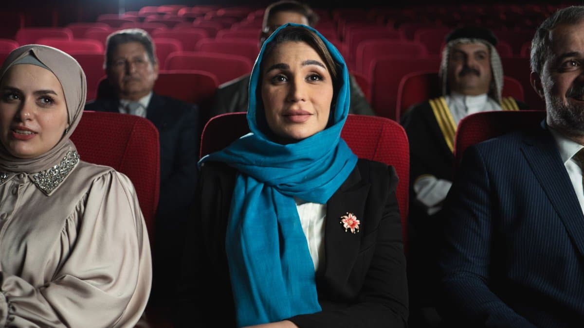 A diverse group of people enjoying a cinematic experience inside a Baghdad theater. Captured in vivid detail.