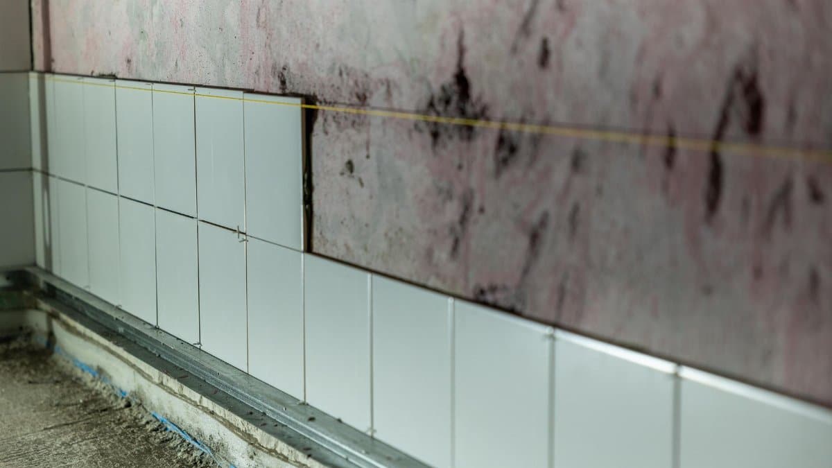 Close-up of partially tiled wall in a construction area, showcasing incomplete renovation work.
