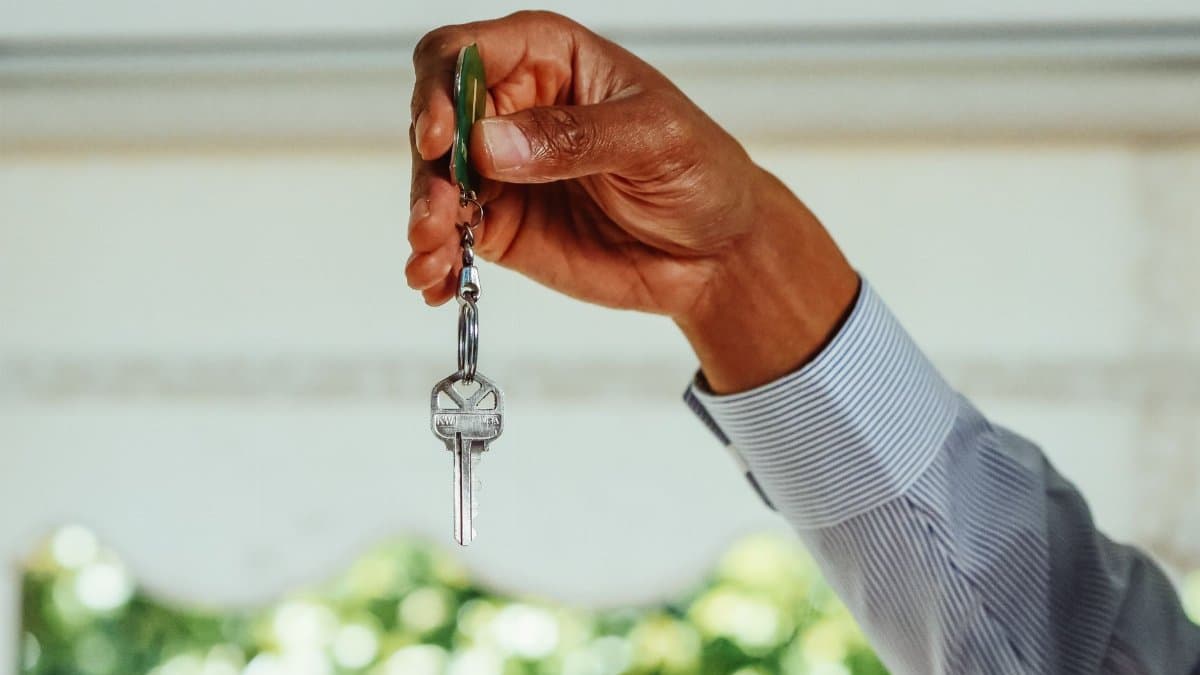 A hand holding a set of house keys, symbolizing buying or renting a new home.