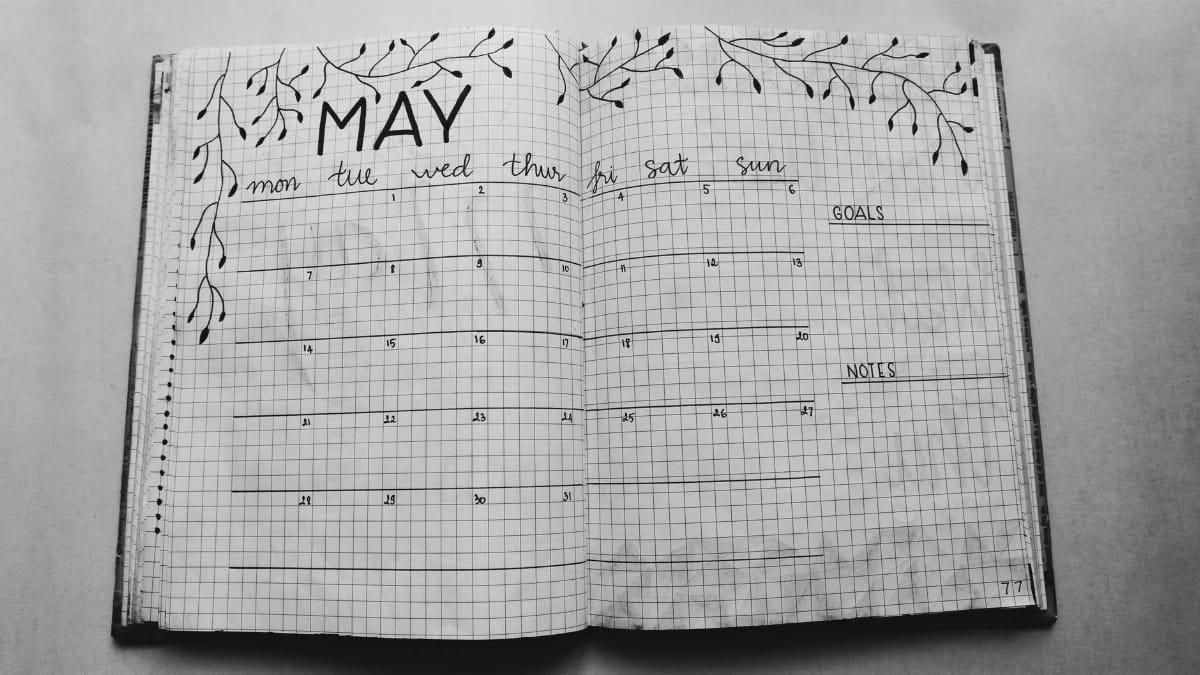 Open notebook displaying a minimalist May planner with handwritten days and decorative elements.
