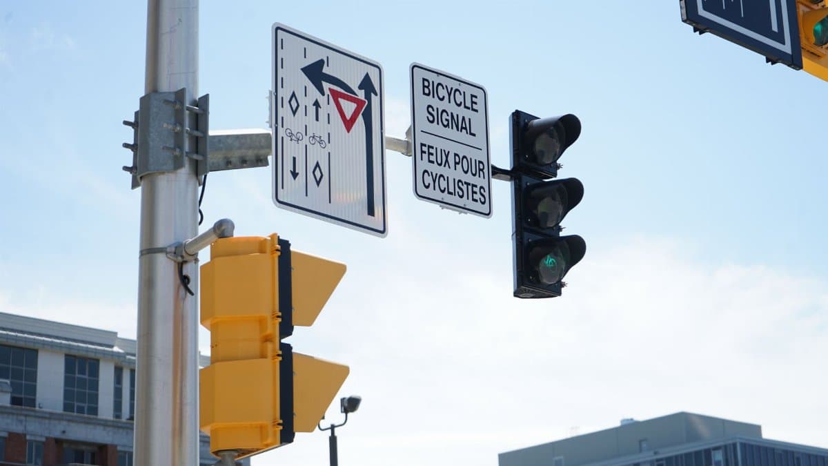 Clear urban intersection with bicycle and traffic signals against a blue sky.