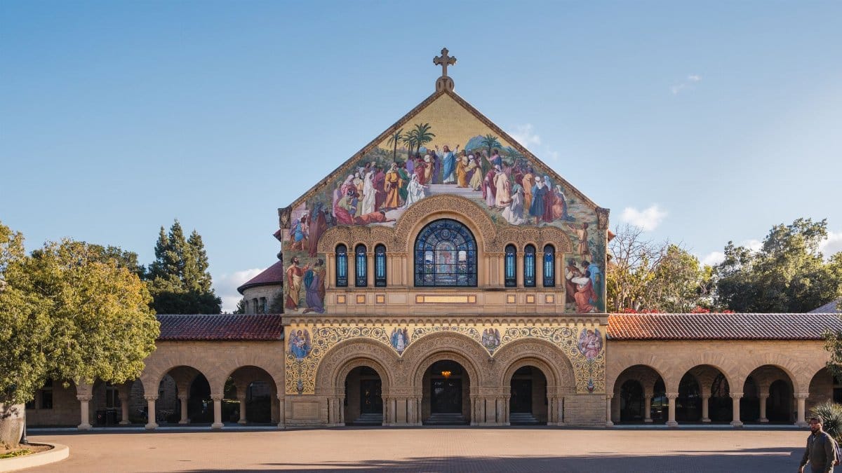 The iconic Stanford Memorial Church with detailed facade under a bright blue sky at Stanford University.