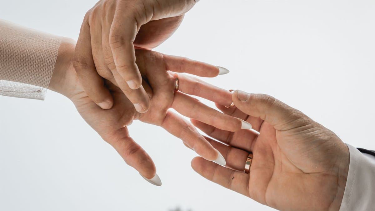Close-up of hands exchanging wedding rings, symbolizing love and commitment in a marriage.