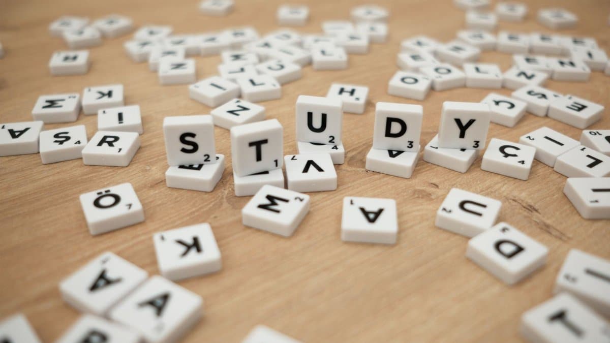 Close-up of letter tiles spelling 'Study' amidst scattered letters on a wooden surface.
