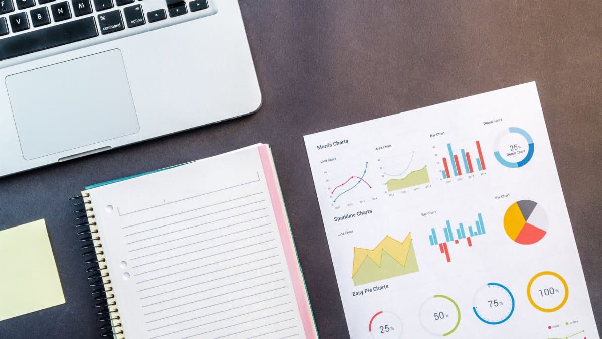 Top view of a laptop, notebook, and data charts on a table, ideal for business and work themes.