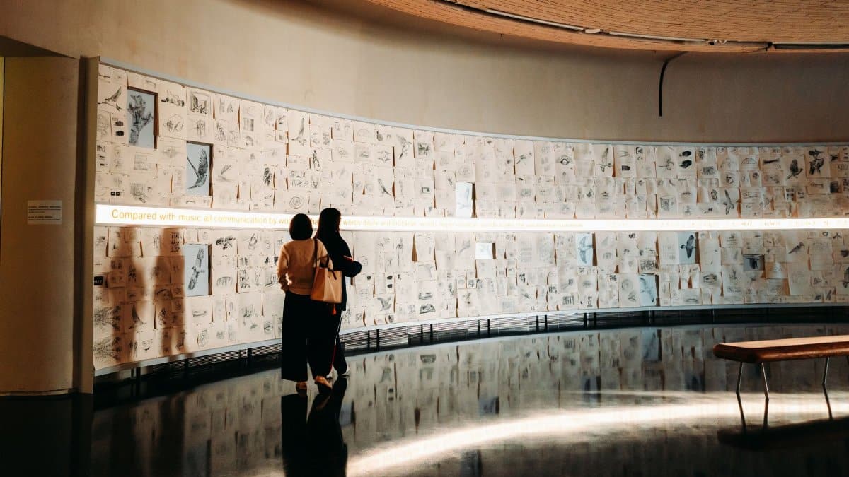 Two people viewing sketches in a modern art gallery. Warm lighting sets an intimate tone.
