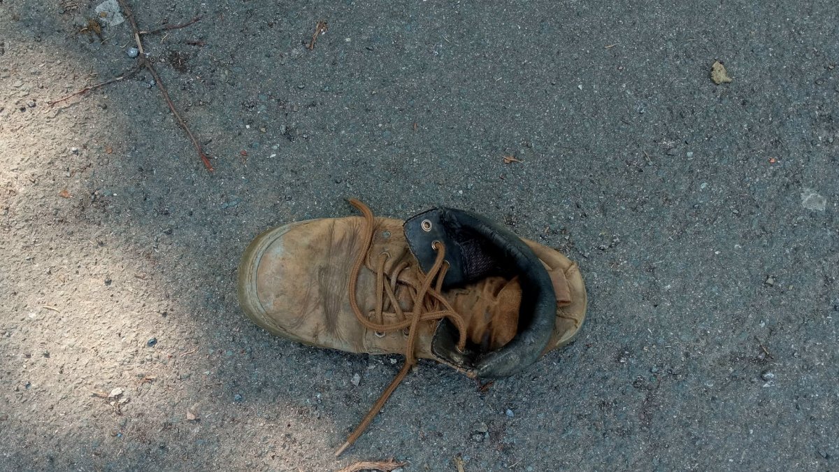 A single worn brown leather boot with laces on a paved surface in Porta Westfalica, Germany.