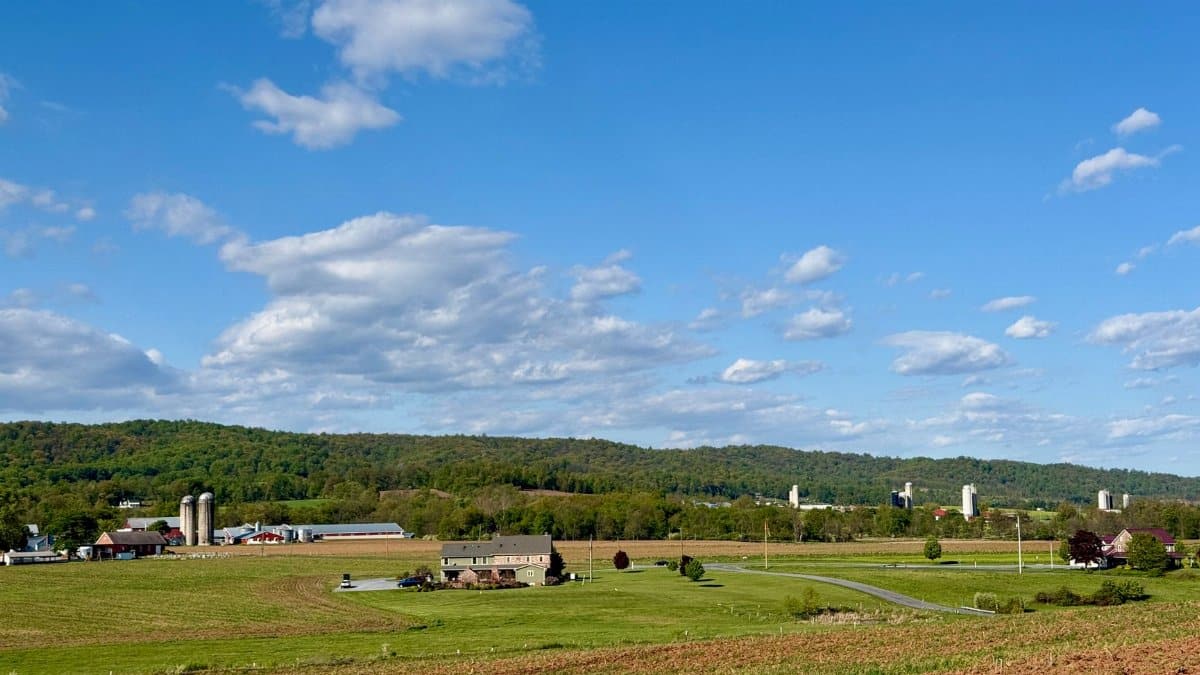 A picturesque view of Pennsylvania farmland under a clear blue sky with rolling hills.