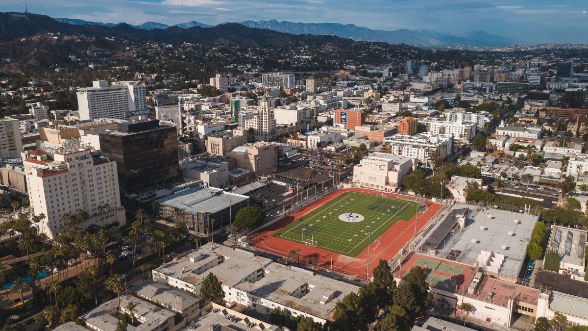 Stunning aerial view of Los Angeles cityscape featuring a prominent football field in the foreground.