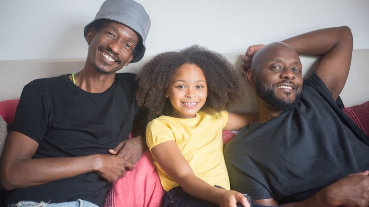 Smiling family relaxing at home on the couch enjoying a TV show and bonding.