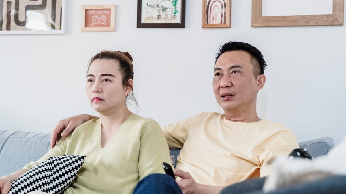 A couple sitting on a comfortable sofa at home in a cozy living room, enjoying a relaxed moment together.