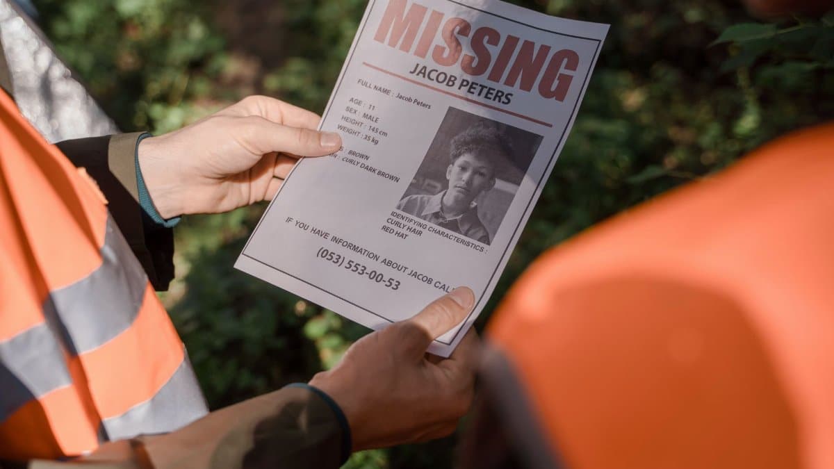 Hands holding a missing person flyer during a search operation in a forest setting, highlighting teamwork and urgency.