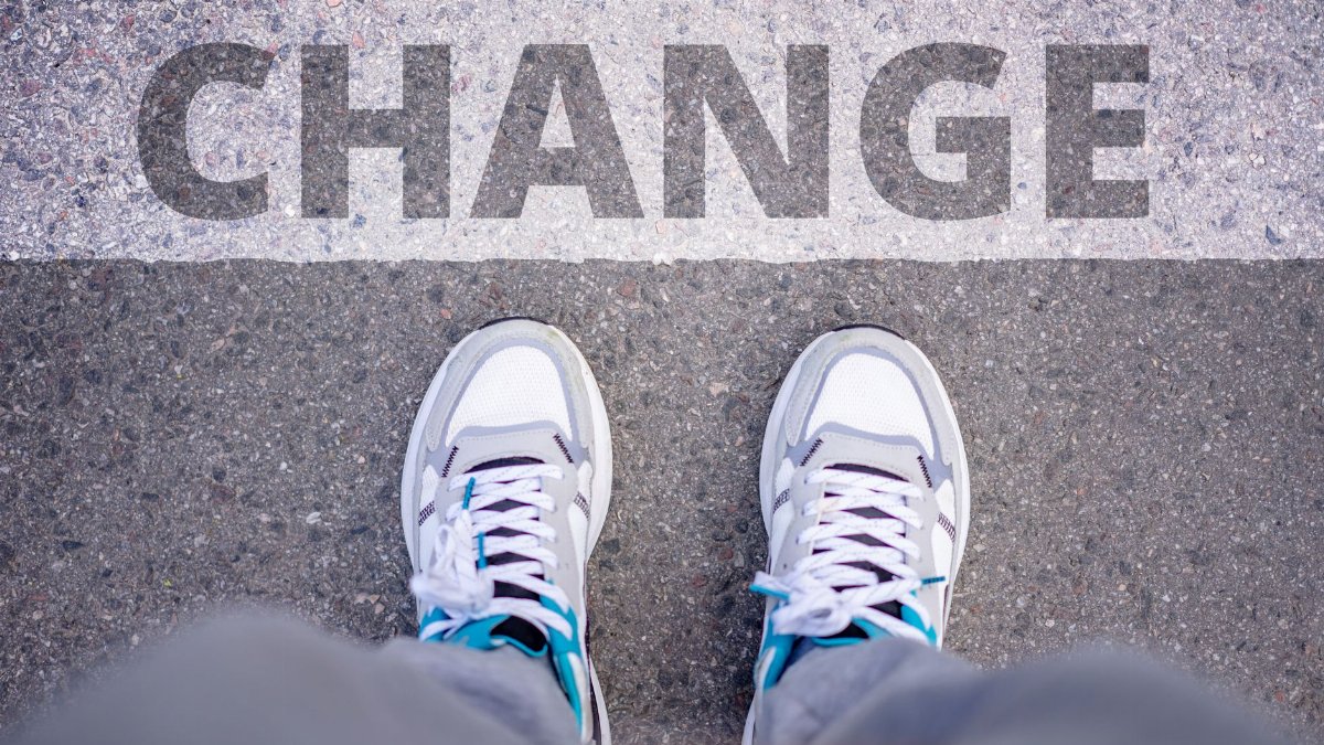 Close-up of sneakers on street with 'Change' text, symbolizing transformation.