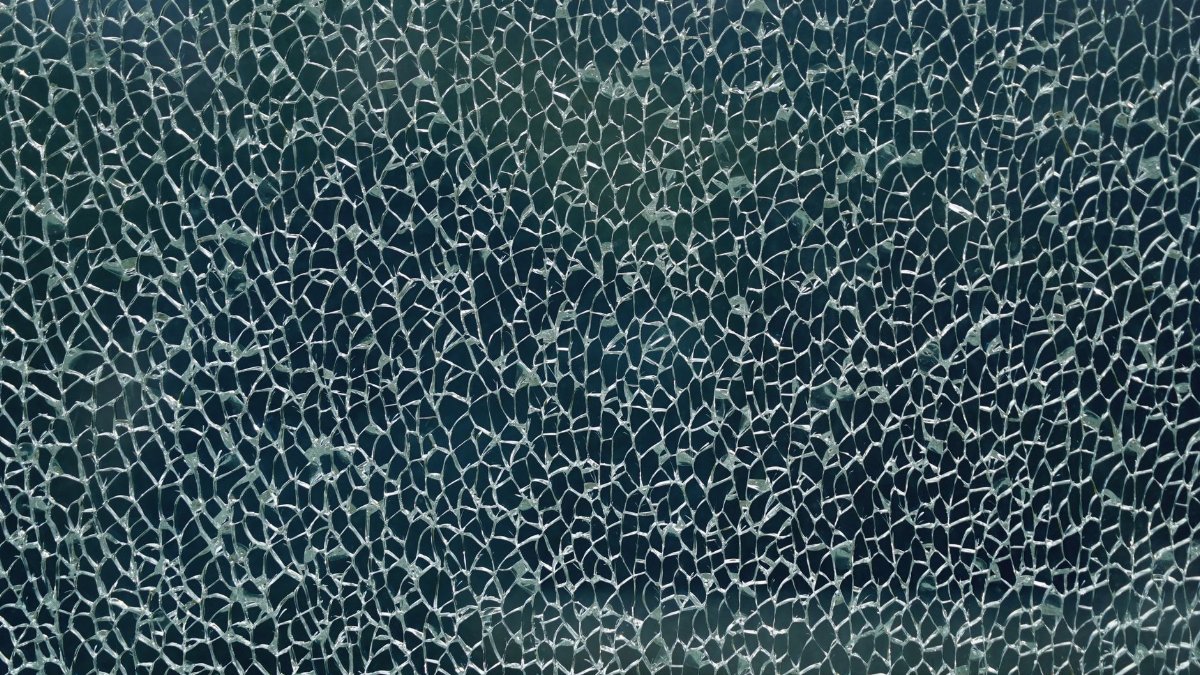 Close-up of shattered glass forming an intricate web-like pattern, showcasing unique texture and abstract forms.