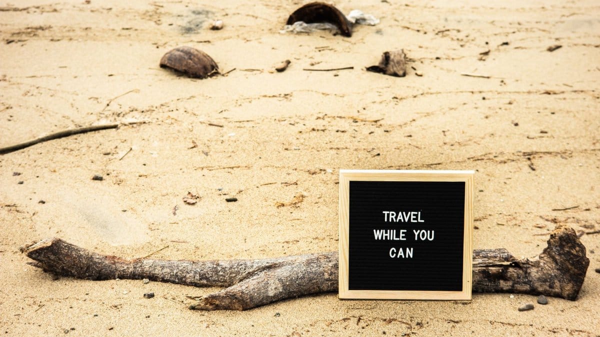 Motivational sign on sandy beach prompts travelers to seize the moment. Perfect for travel inspiration.