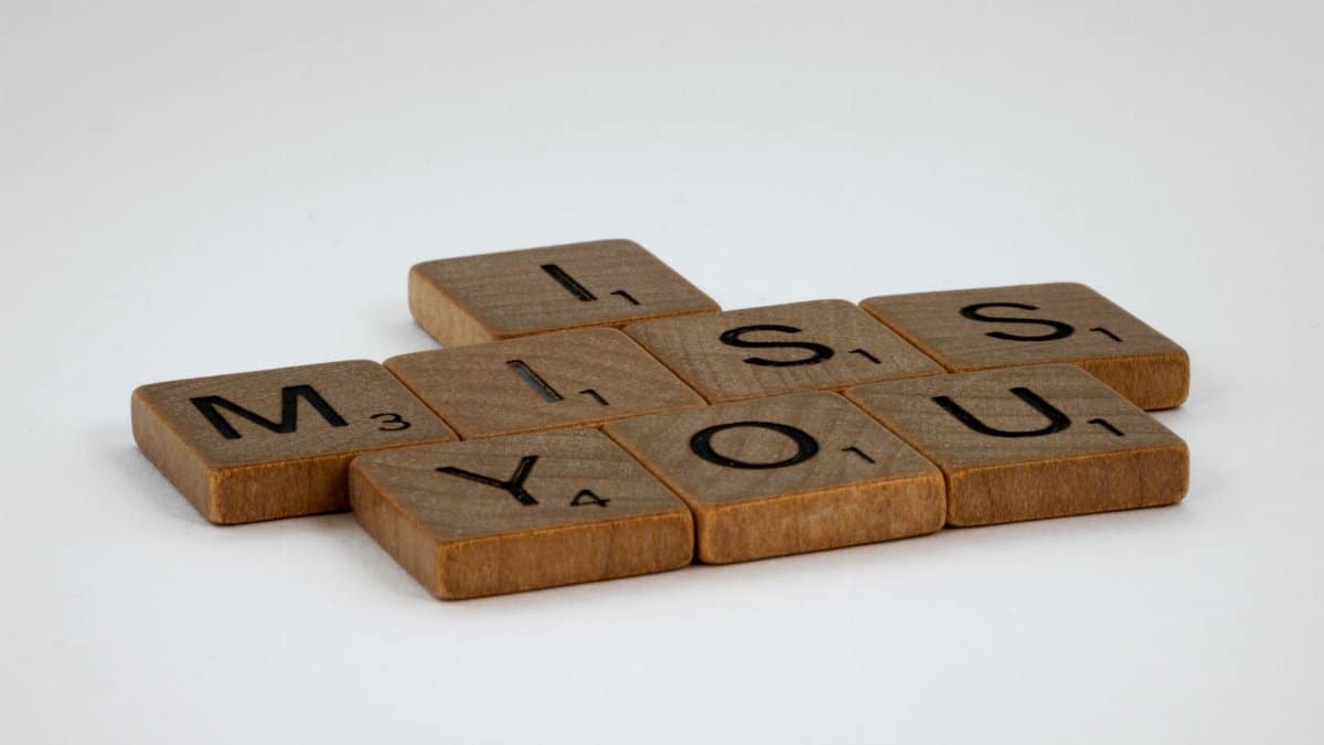 Close-up of Scrabble tiles spelling 'I Miss You' on a white surface with ample copy space.