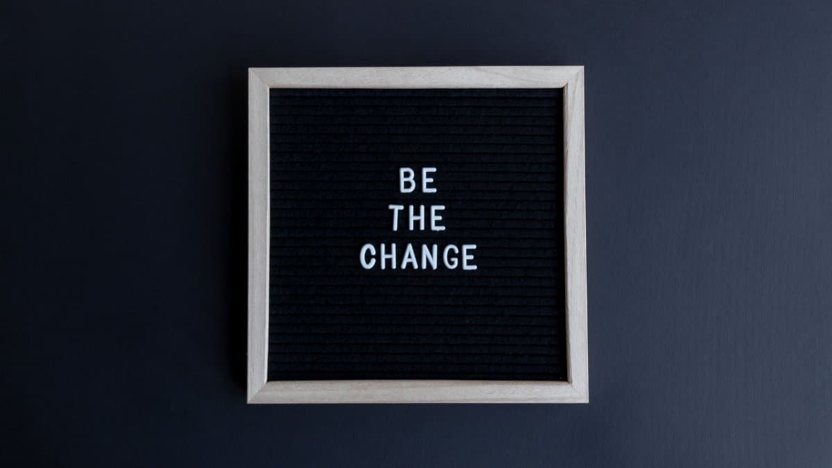 A simple letter board with the motivational message 'Be the Change' on a dark background.