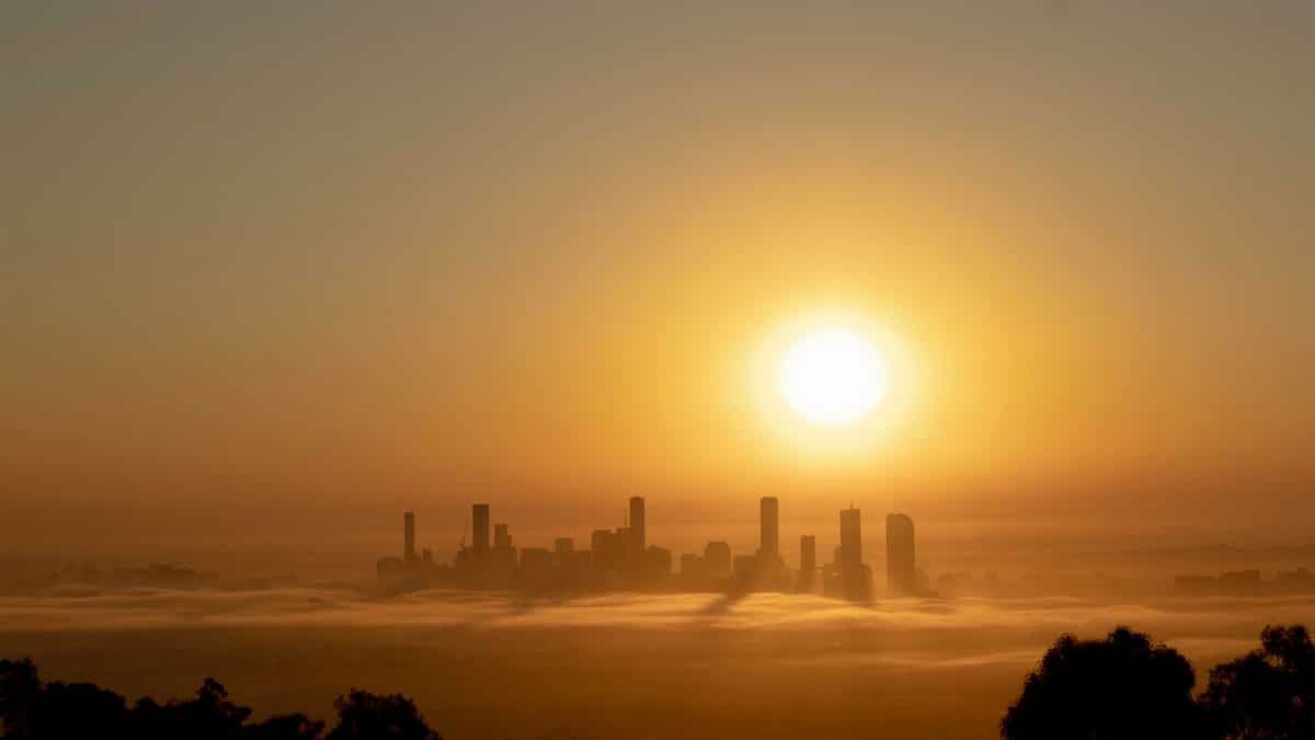 Stunning sunrise view of Brisbane city skyline enveloped in fog, creating a serene and golden atmosphere.