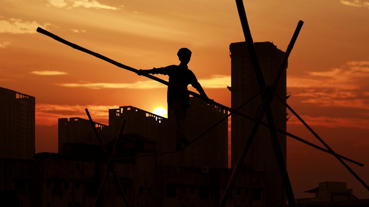 A man performing acrobatics against a dramatic sunset in Bhiwandi, India.