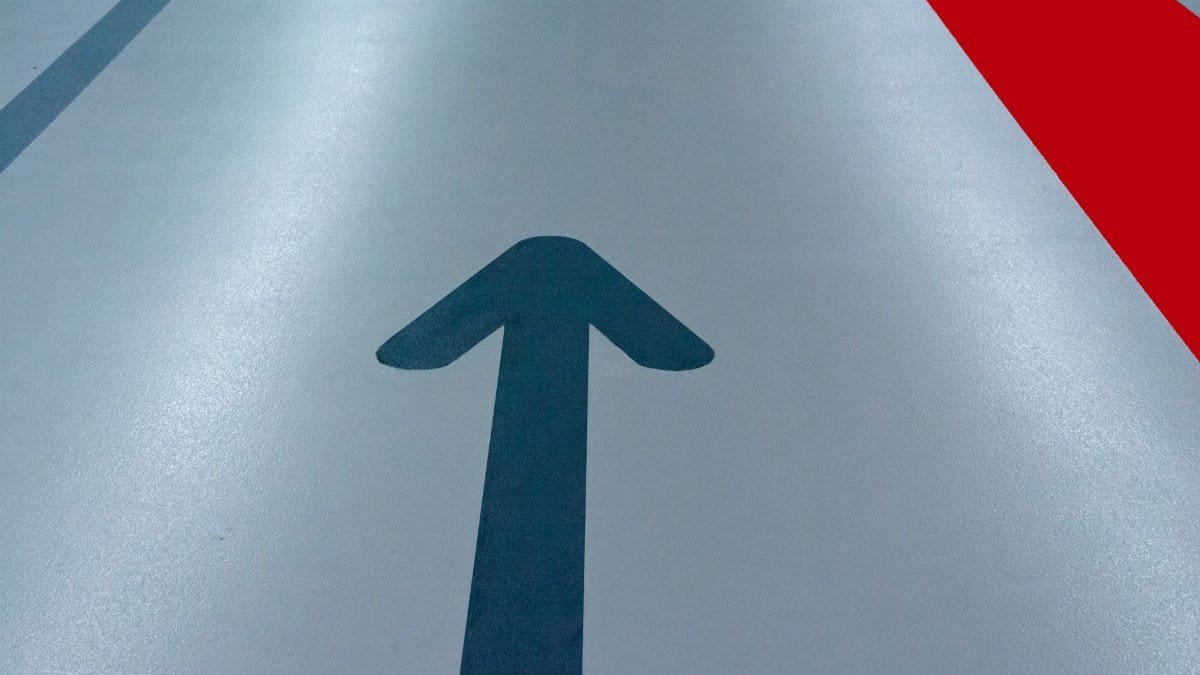 Blue arrow and red line on a parking garage floor signify direction and order.
