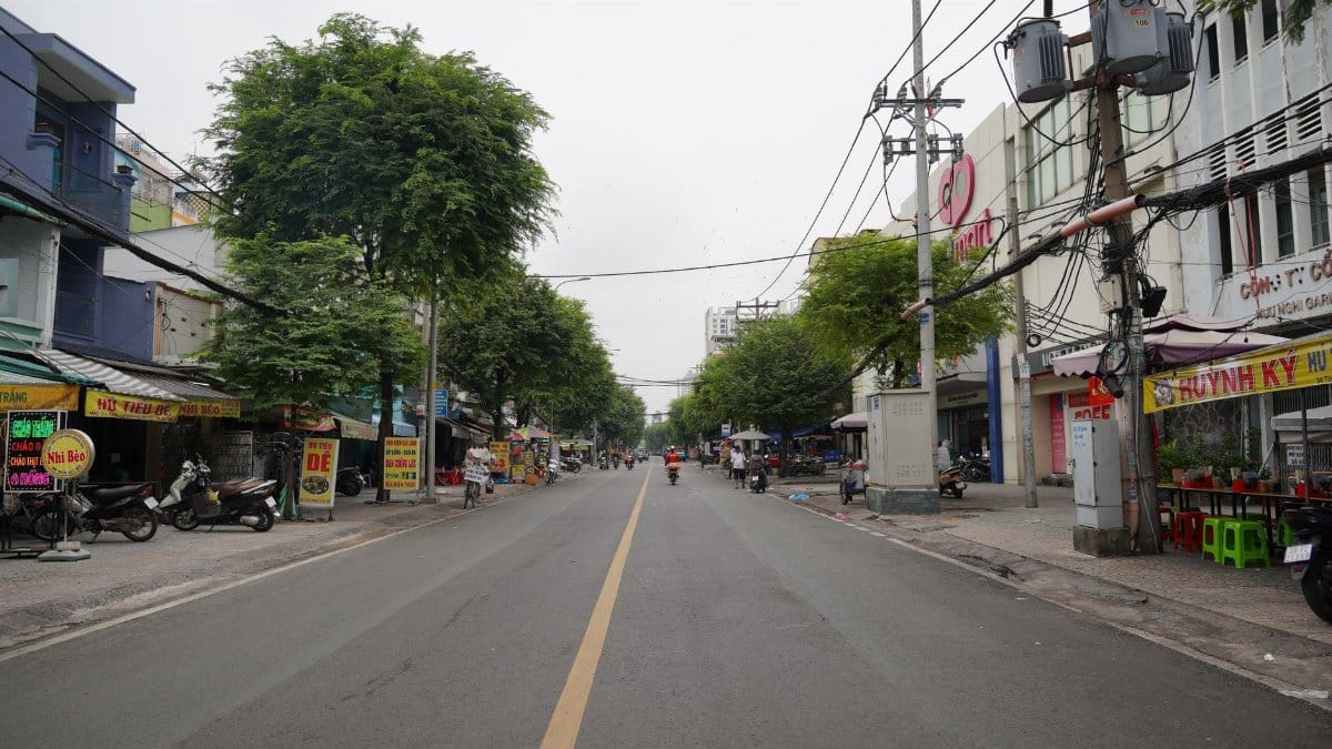 Quiet street lined with shops and trees in an urban setting.