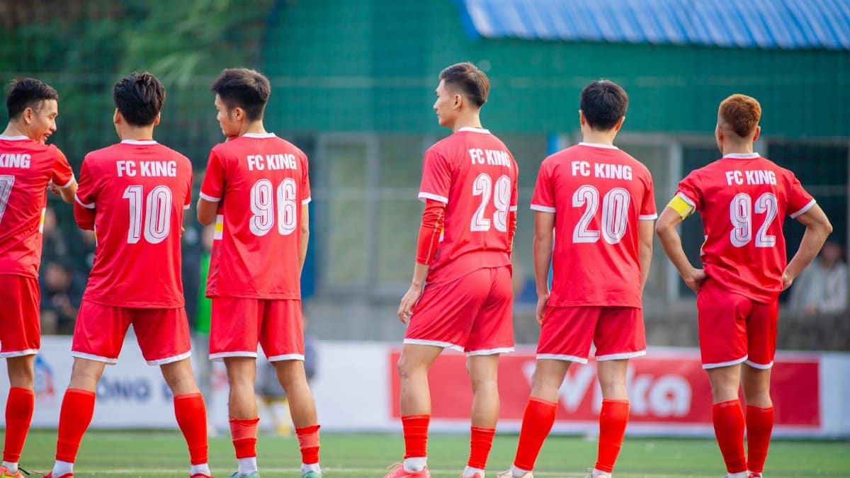 Football players in red uniforms from FC King standing on a field in Hà Nội, Vietnam.
