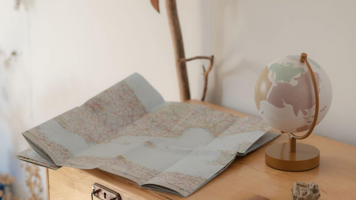 Cozy setting of a vintage map and globe on a wooden table, symbolizing travel exploration.