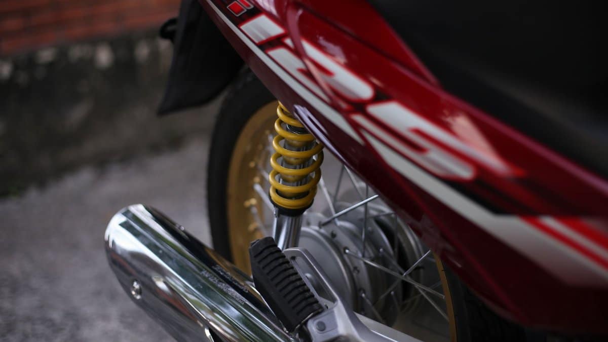 Detailed close-up of a motorcycle rear suspension highlighting metallic and rubber components.