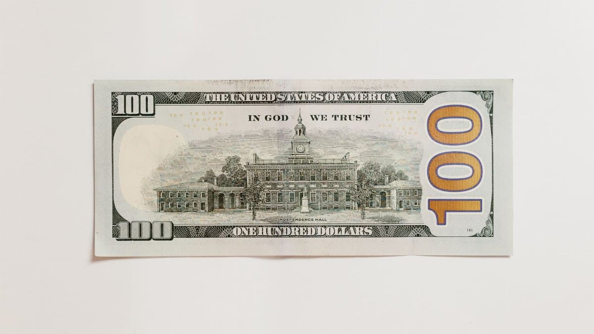 Detailed close-up of an American one hundred dollar bill on a neutral white background.